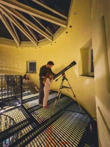 Family stargazing with a telescope beneath the Witches Mill glass rooftop