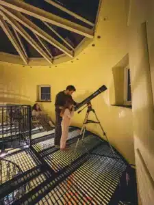 Family enjoying the telescope beneath the glass rooftop of the Witches Mill.